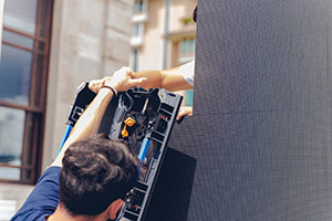 Technicians installing a modular LED video wall at an event.