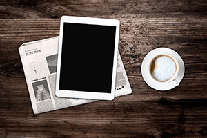 Desk with an iPad, Business newspaper, and Coffee.